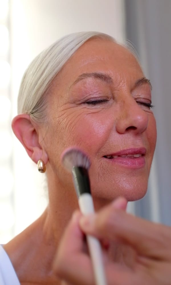 Frau mittleren Alters mit UND GRETEL Blush Auftrag